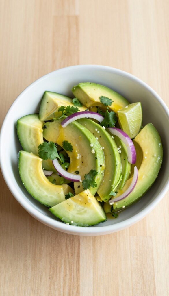 Creamy avocado lime cucumber salad in a white bowl on a wooden table