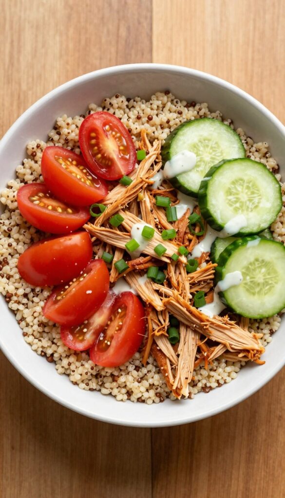 Buffalo chicken salad grain bowl with quinoa, cherry tomatoes, cucumber, and ranch dressing