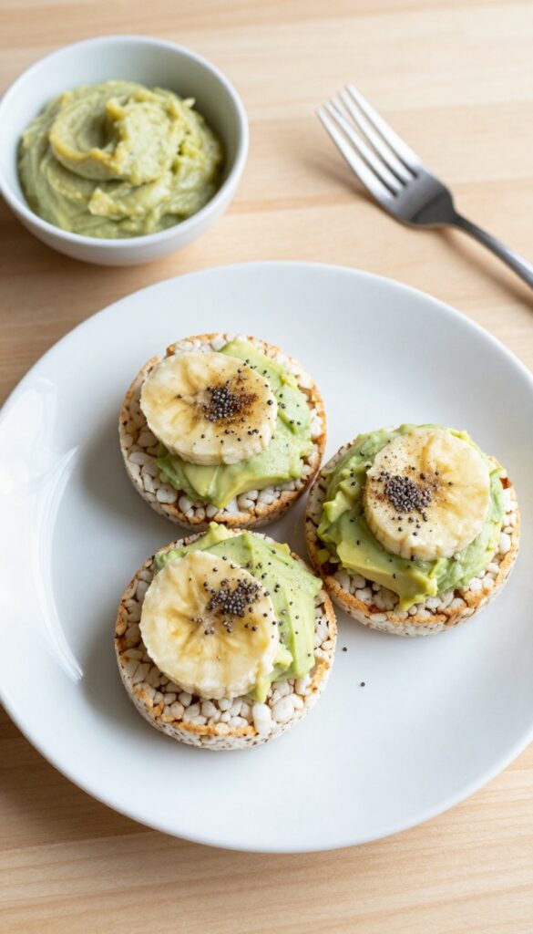 Rice cakes topped with avocado and banana mash on a white plate