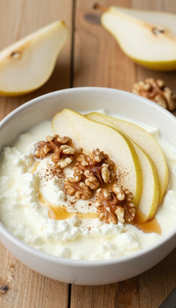 Cottage cheese bowl with pear slices, walnuts, and maple syrup drizzle on a wooden table.